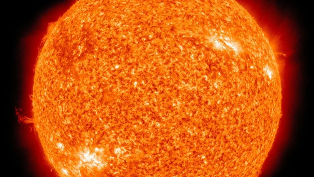 Vibrant orange-red close-up of the Sun showing a highly textured surface with fine solar structures.