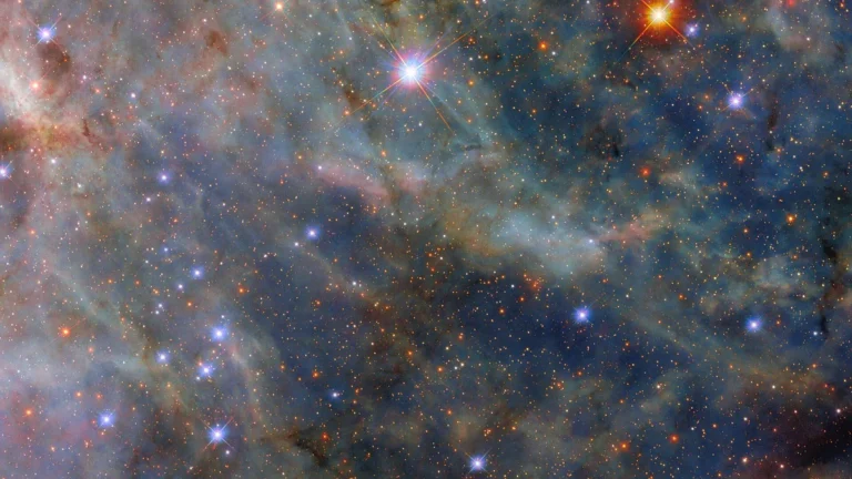 A vibrant field of stars and colorful cosmic dust clouds in deep space.