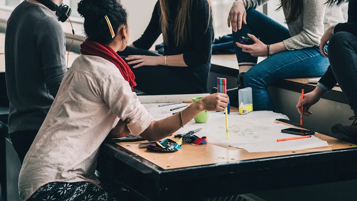 People collaborating on papers with colorful markers at a table, depicting teamwork and project planning.