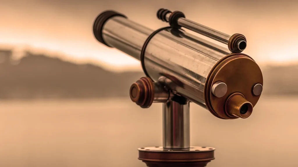A metallic telescope on a stand points toward a warm, hazy horizon under a golden sky.