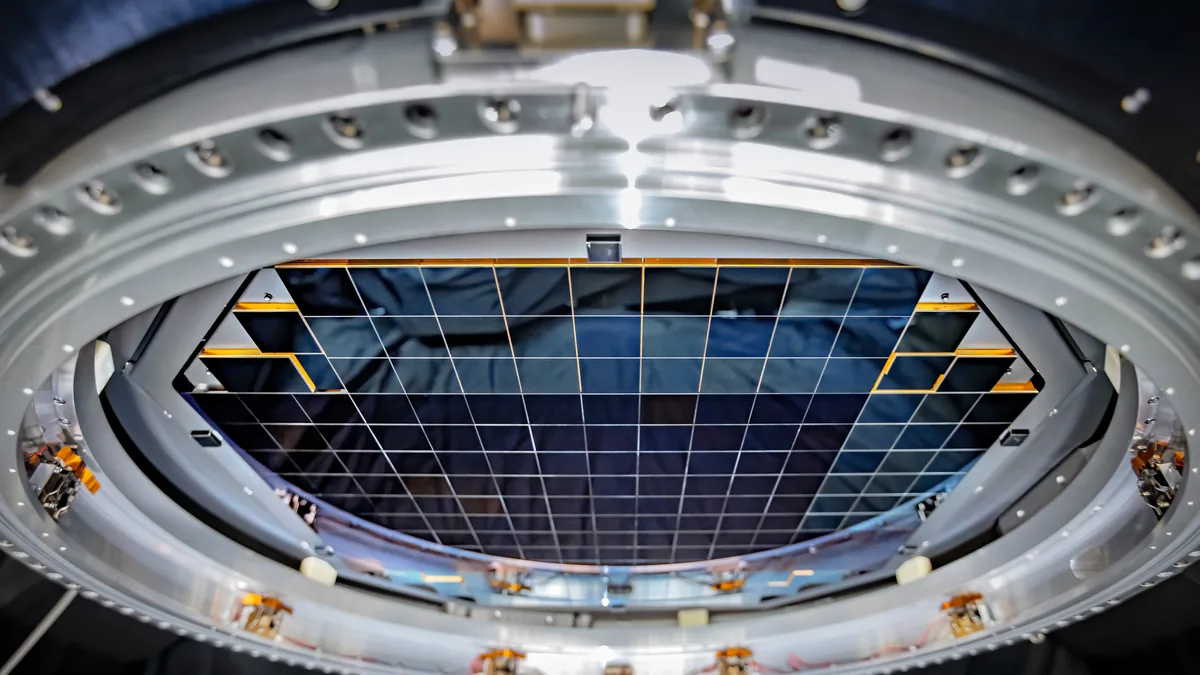 Close-up of the grid-like sensor array of a large astronomical camera inside a metallic ring.