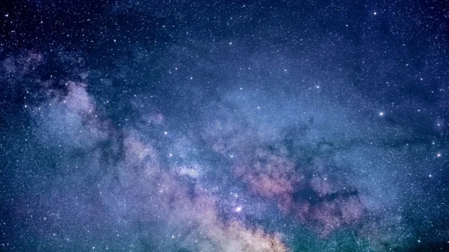 A vibrant, colorful view of the Milky Way galaxy filled with stars and purple nebulae.