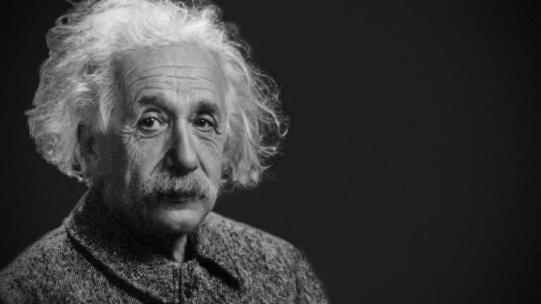 Black and white portrait of Albert Einstein, showing his iconic white hair and mustache against a dark background.