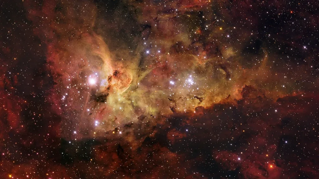 Colorful cosmic nebula filled with bright stars and glowing red and orange gas clouds, depicting a stellar nursery.